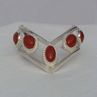 Five fouteen by ten millimeter oval Red Jasper stones bezel set connected by two triangular wires which are formed to a chevron shape. Worn with chevron pointing down